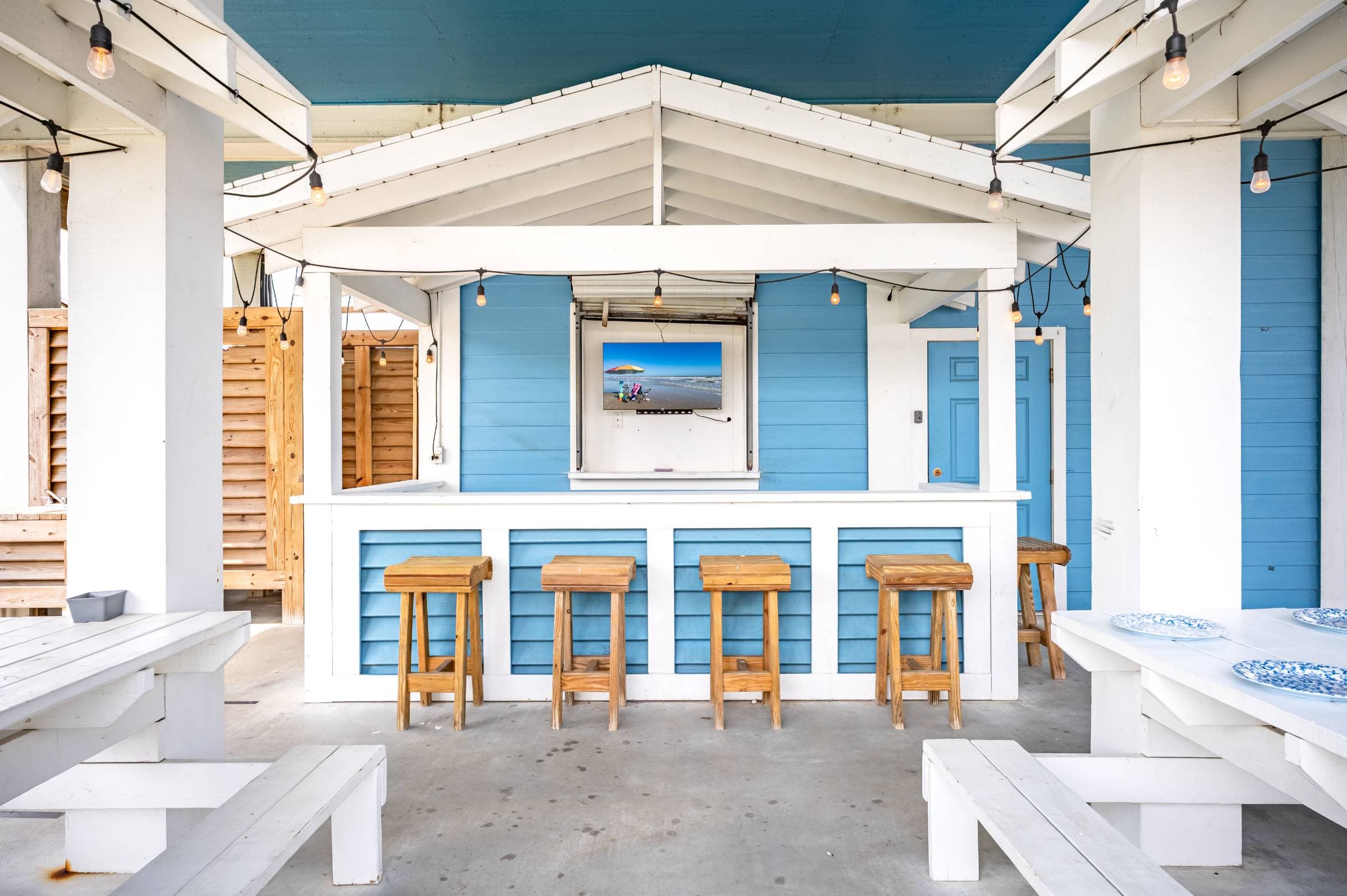 Gather at the outdoor bar at Crystal Waters Beach House—featuring bar seating, a TV, two large covered picnic tables, with the hot tub and a bathroom just steps away for ultimate convenience.